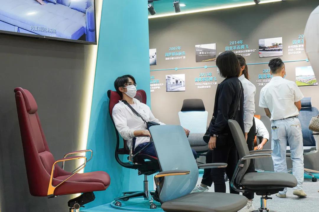 圖丨客商們在迪歐展位現(xiàn)場體驗辦公坐具的產品性能